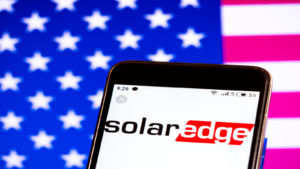 SolarEdge logo on phone with American flag background. SEDG stock