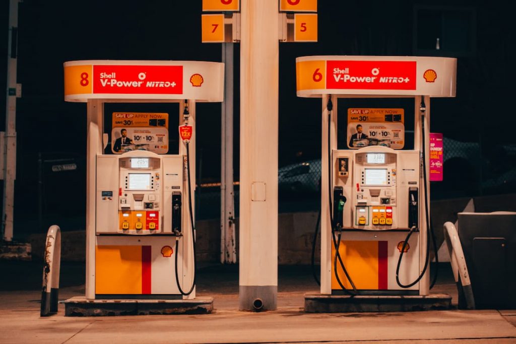 Two Shell petrol pumps side-by-side on a garage fourecourt at night